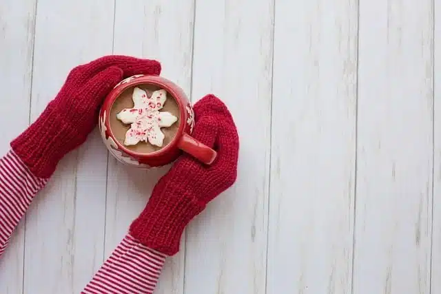 Chocolat chaud maison tenu par des mains avec des moufles