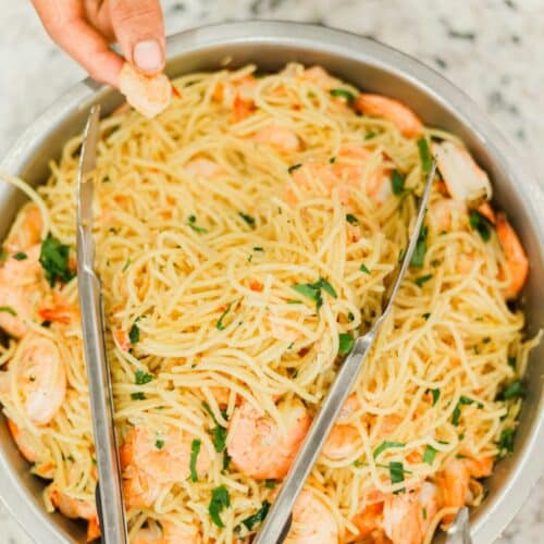 person holding stainless steel bowl with noodles