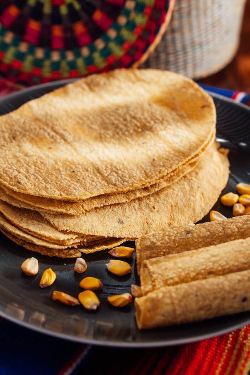 Authentic corn tortillas stacked with corn kernels on a plate, perfect for a traditional meal.
