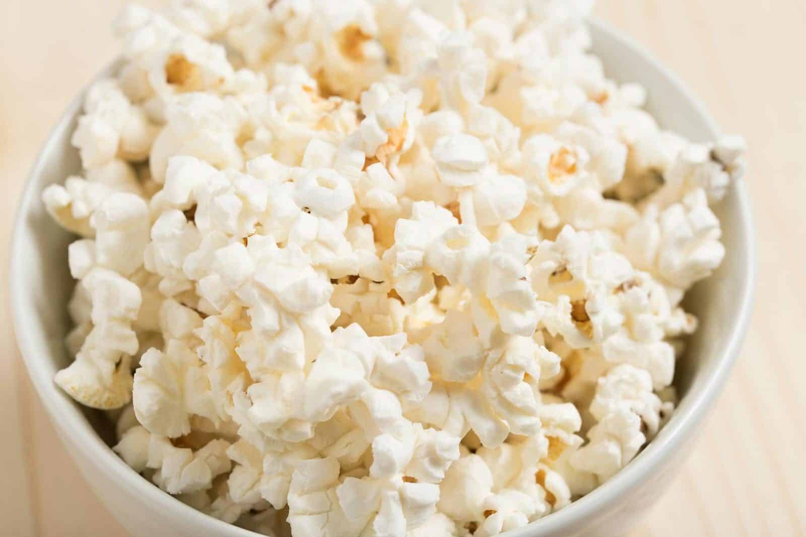 Close-up of freshly popped popcorn in a white bowl, perfect for a movie night snack.