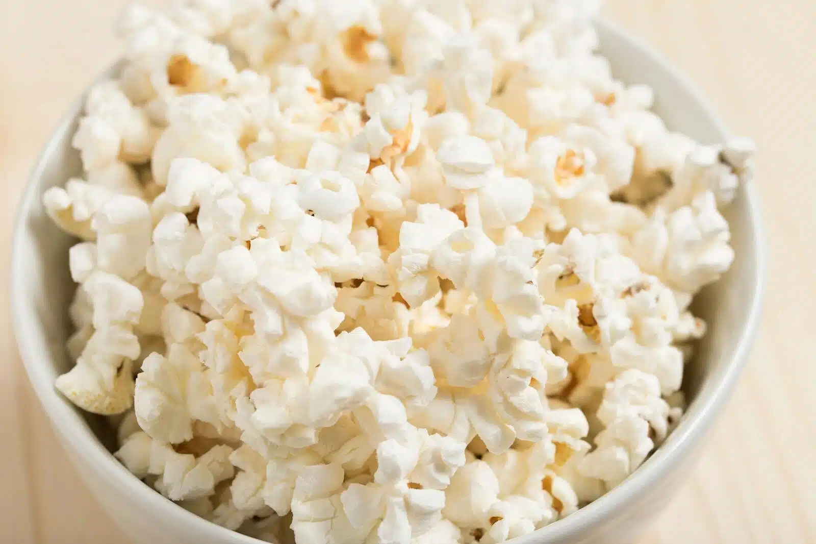 Close-up of freshly popped popcorn in a white bowl, perfect for a movie night snack.