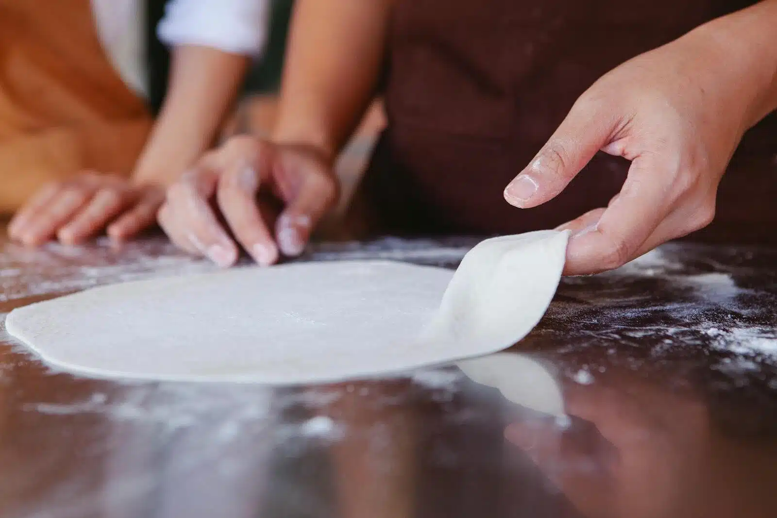 Close-up of hands shaping pizza dough on a floured surface, highlighting artisanal cooking.