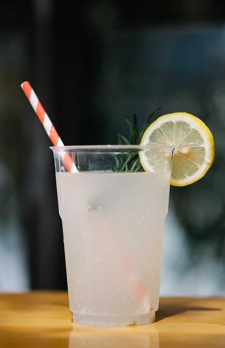 Close-up of a cool lemonade with mint and lemon in a transparent cup, refreshing summer beverage.