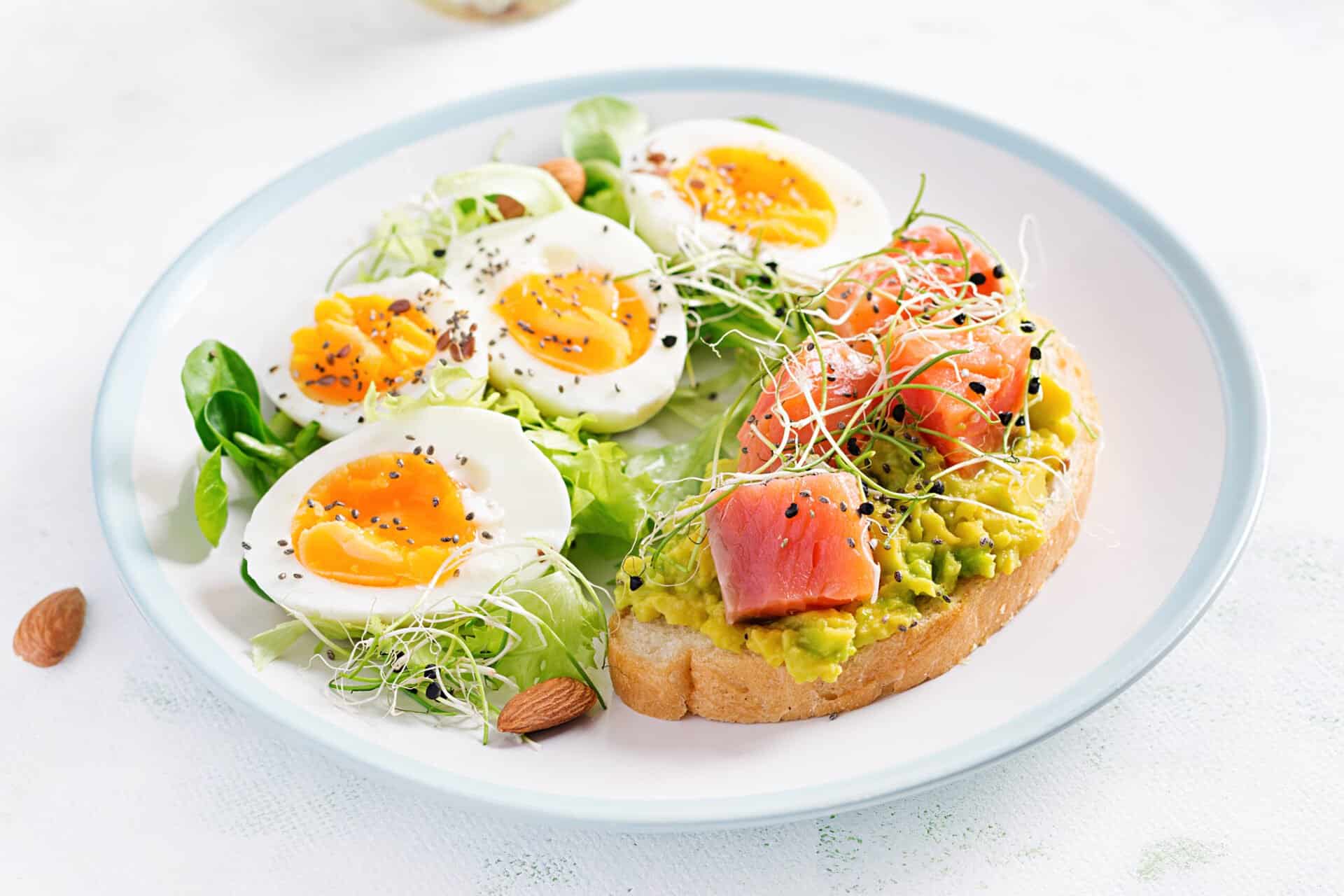 Breakfast Healthy Open Sandwich On Toast With Avocado And Salmon Boiled Eggs Herbs Chia Seeds On White Plate With Copy Space Healthy Protein Food