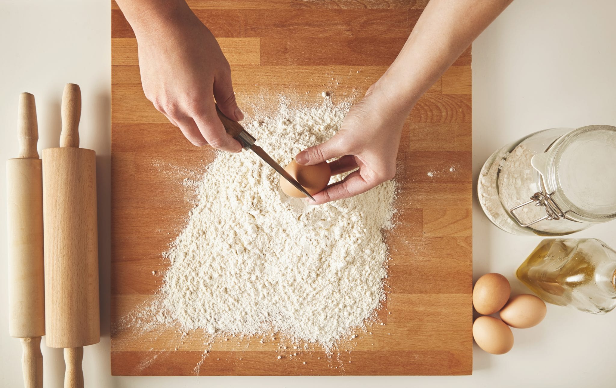Person Ready To Break Chicken Eggs Above White Flour Scaled